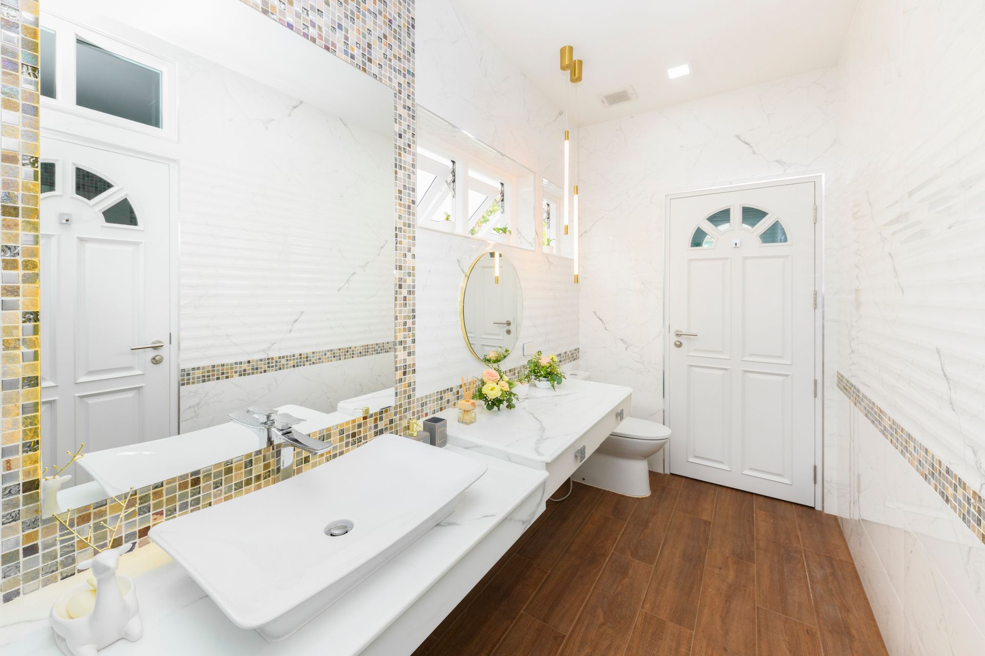 Modern bathroom remodeling with white marble walls, wooden floor, and decorative tiles.