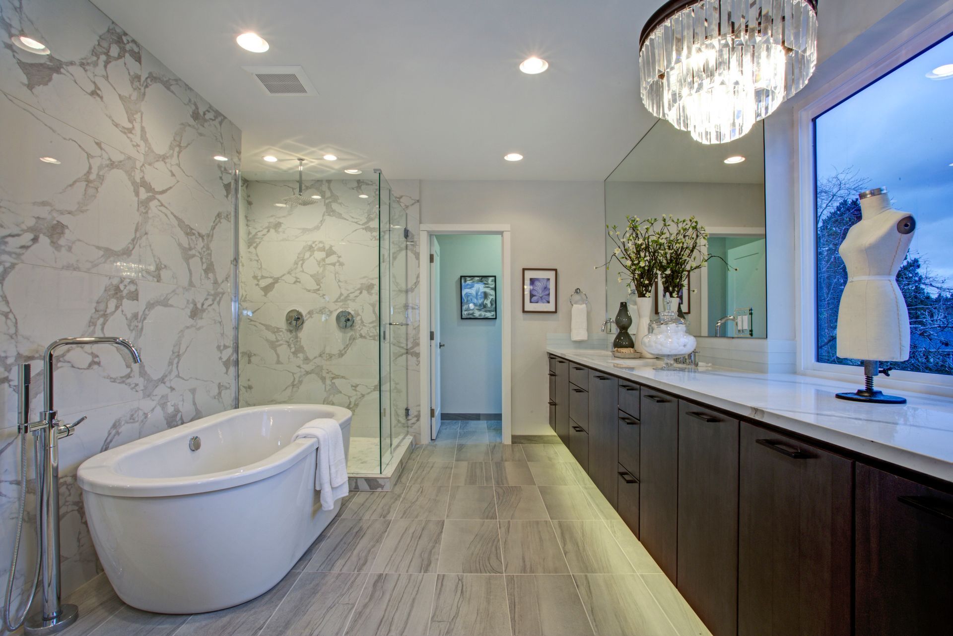 White and gray marble bathroom remodel, with tiled floors, quartz counters, and floating cabinets.