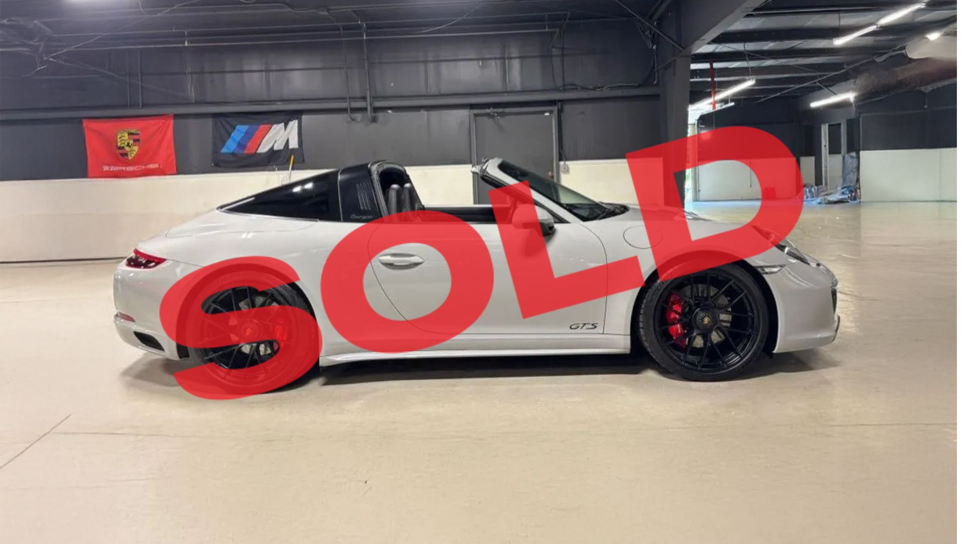 Black sports car in an indoor showroom with a large red