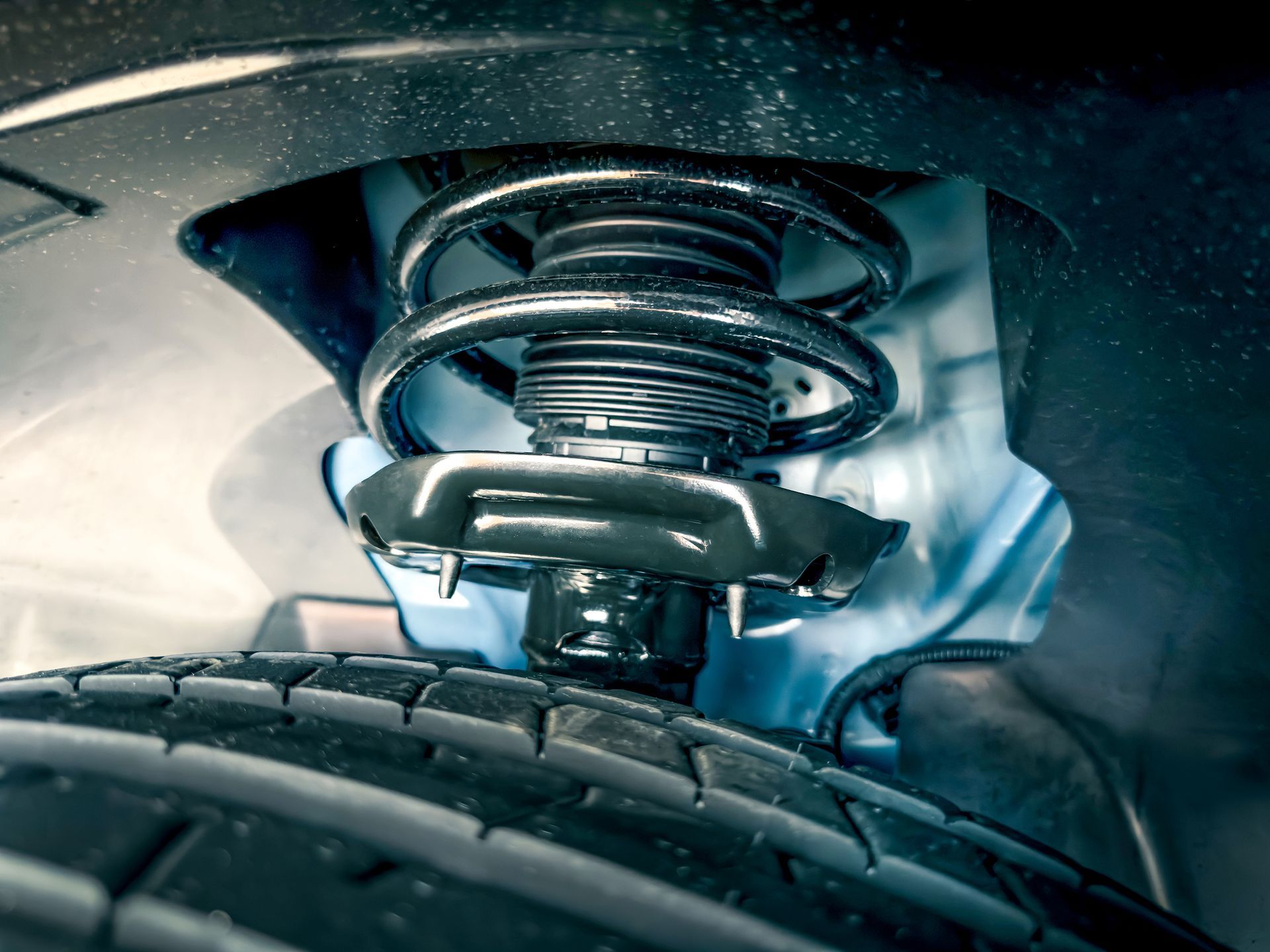 Car suspension system, black coil spring, damper, and tire viewed from below.