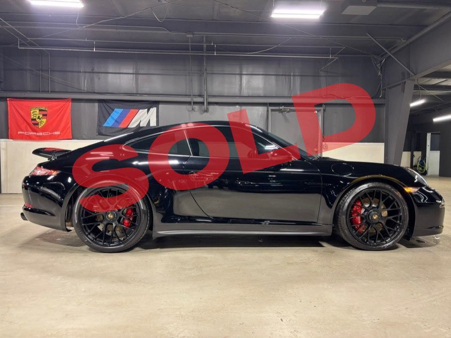 Black sports car in an indoor showroom with a large red
