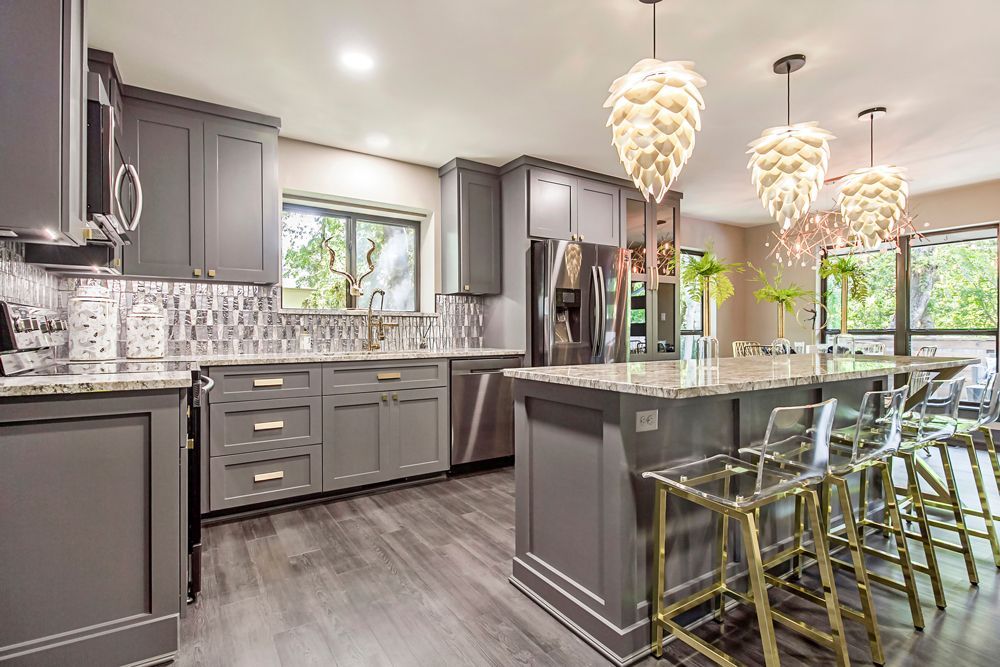 a kitchen with gray cabinets , granite counter tops , stainless steel appliances , and a large island .