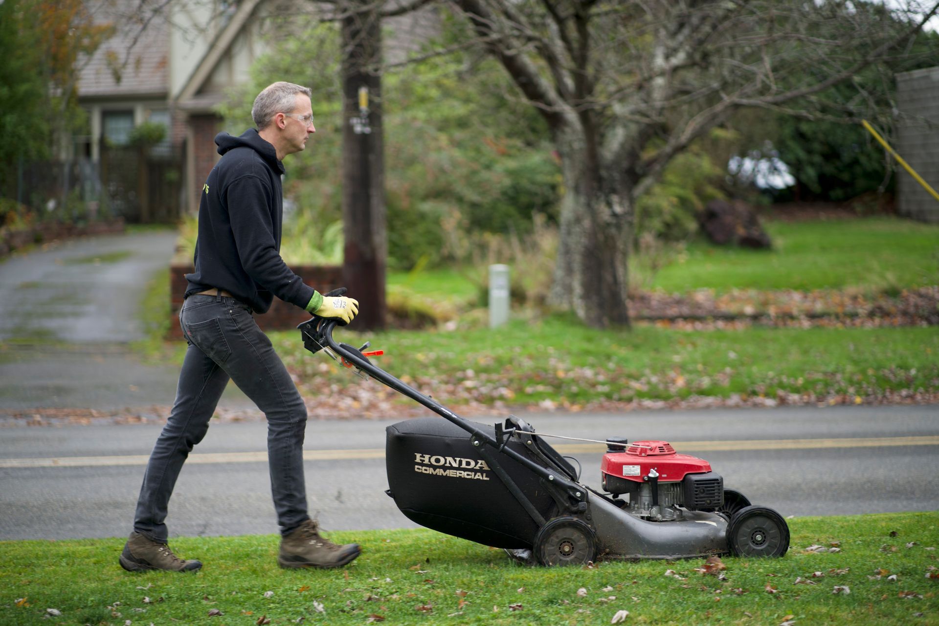 A man is pushing a lawn mower down a lush green lawn.