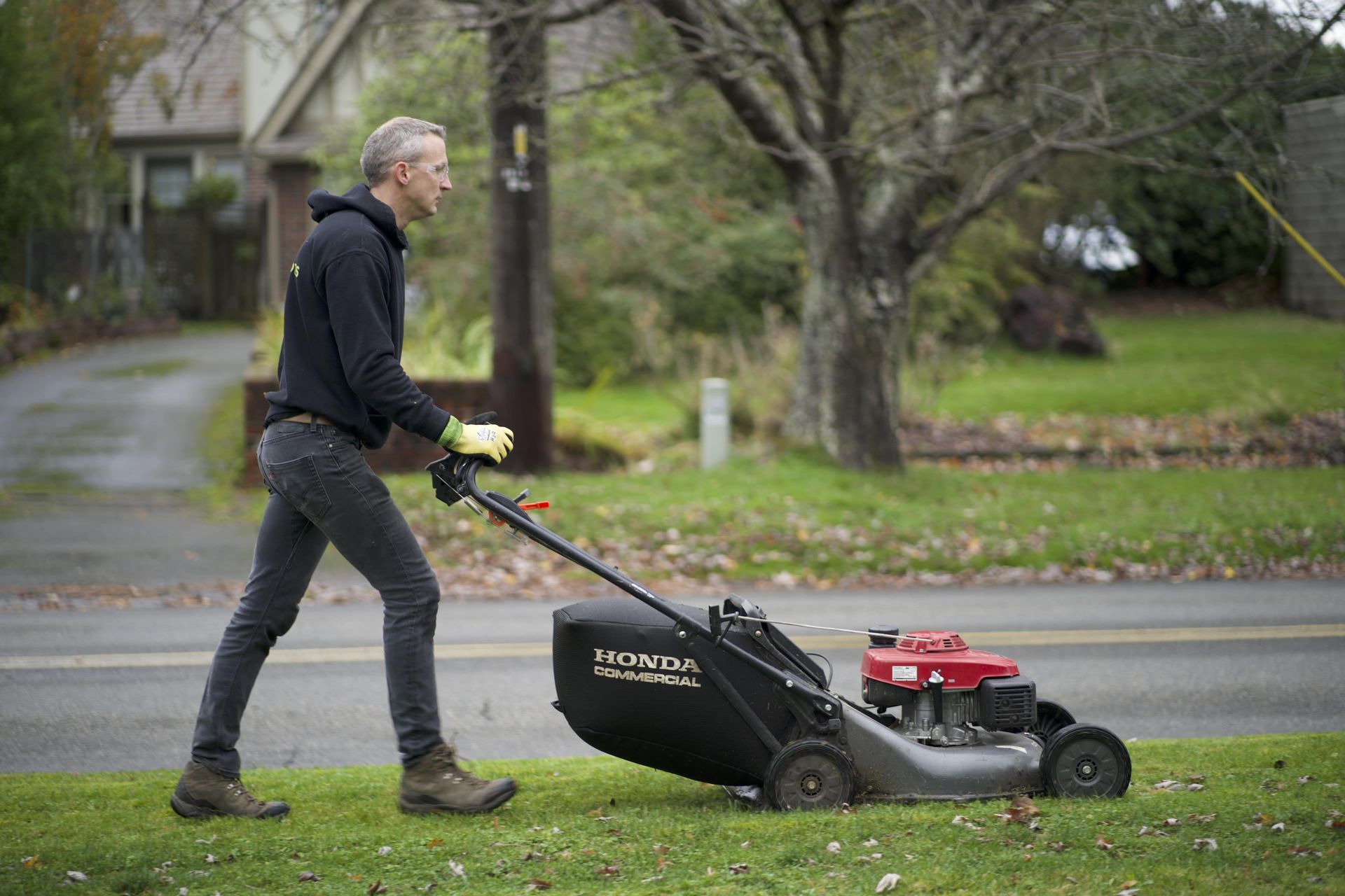 A man is pushing a lawn mower down a lush green lawn.