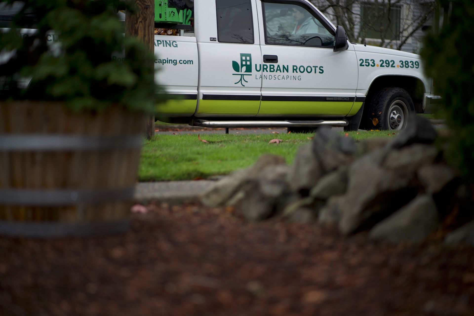 A white and green truck is parked on the side of the road.