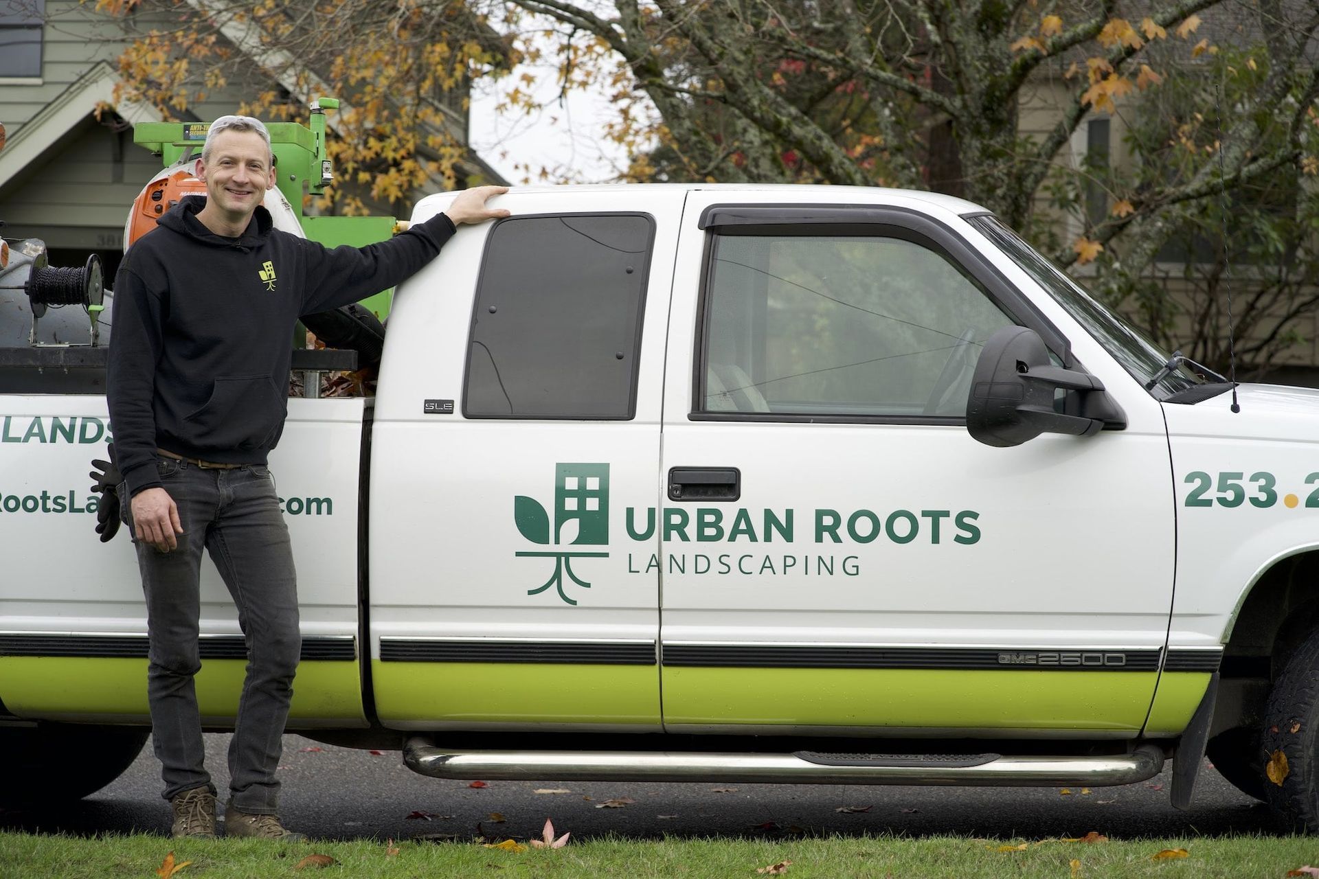 A man is standing next to a truck that says urban roots landscaping.