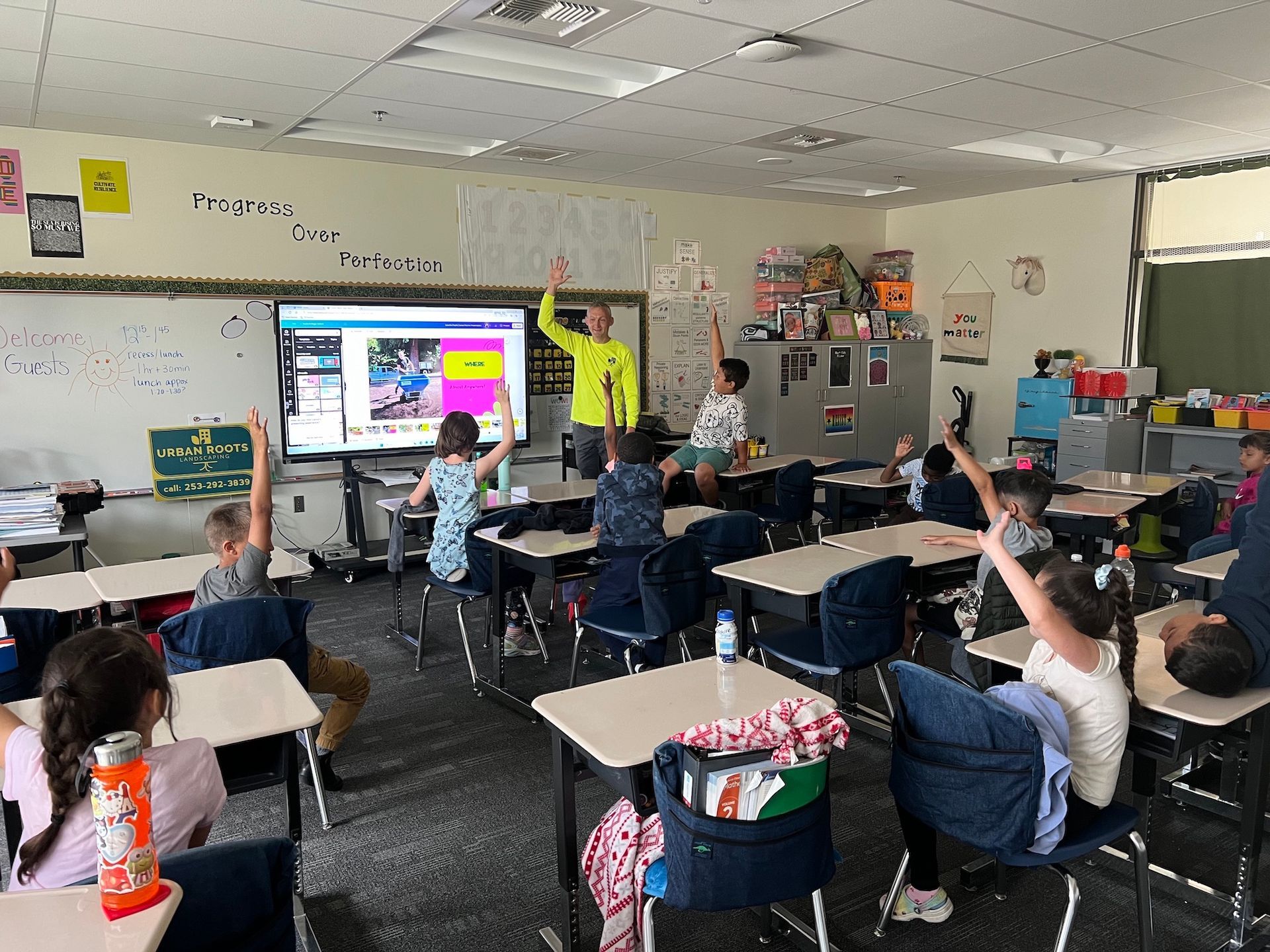 A group of children are raising their hands in a classroom.