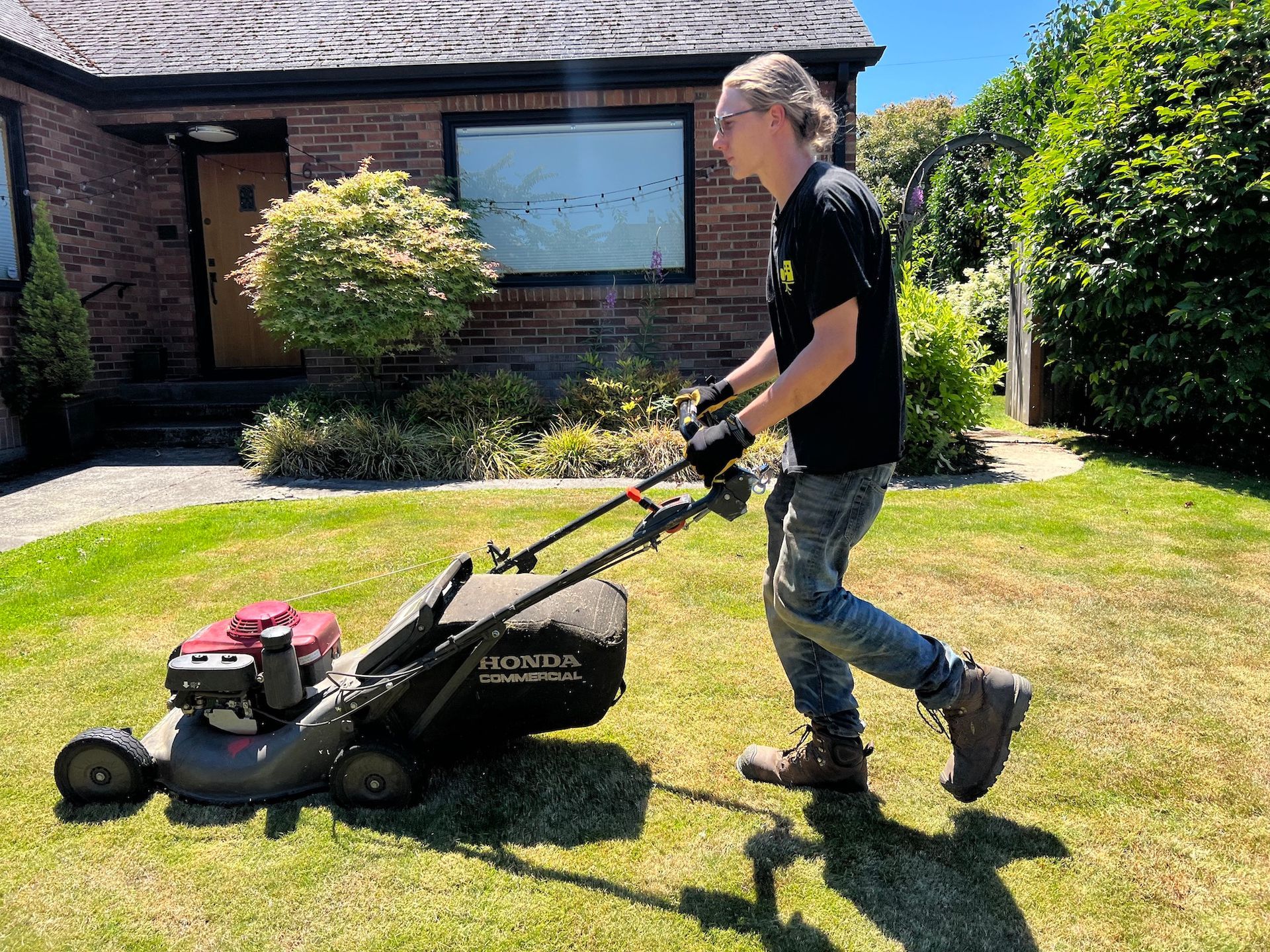 A man is pushing a lawn mower on a lush green lawn.