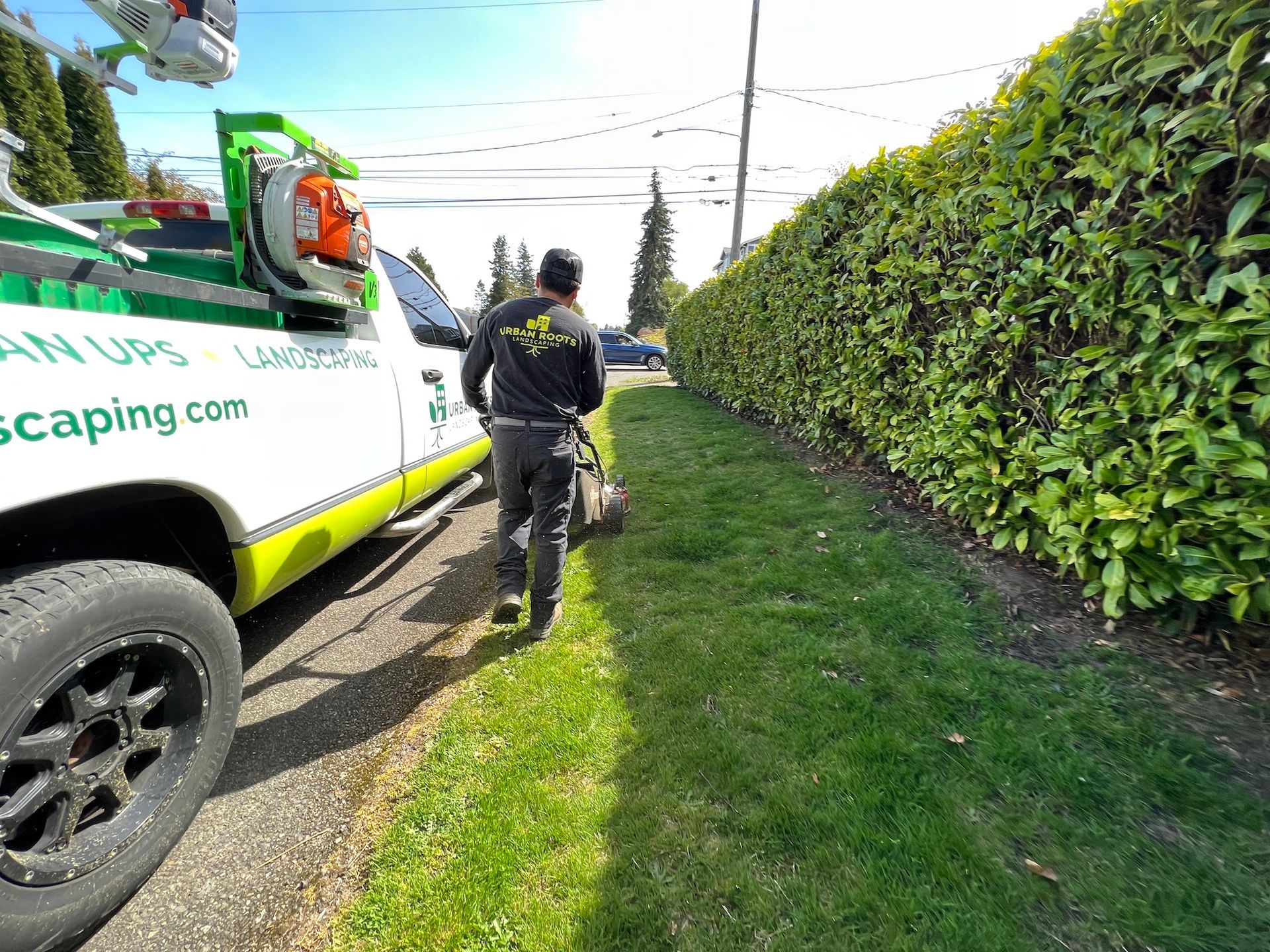 A man is mowing the grass next to a truck.