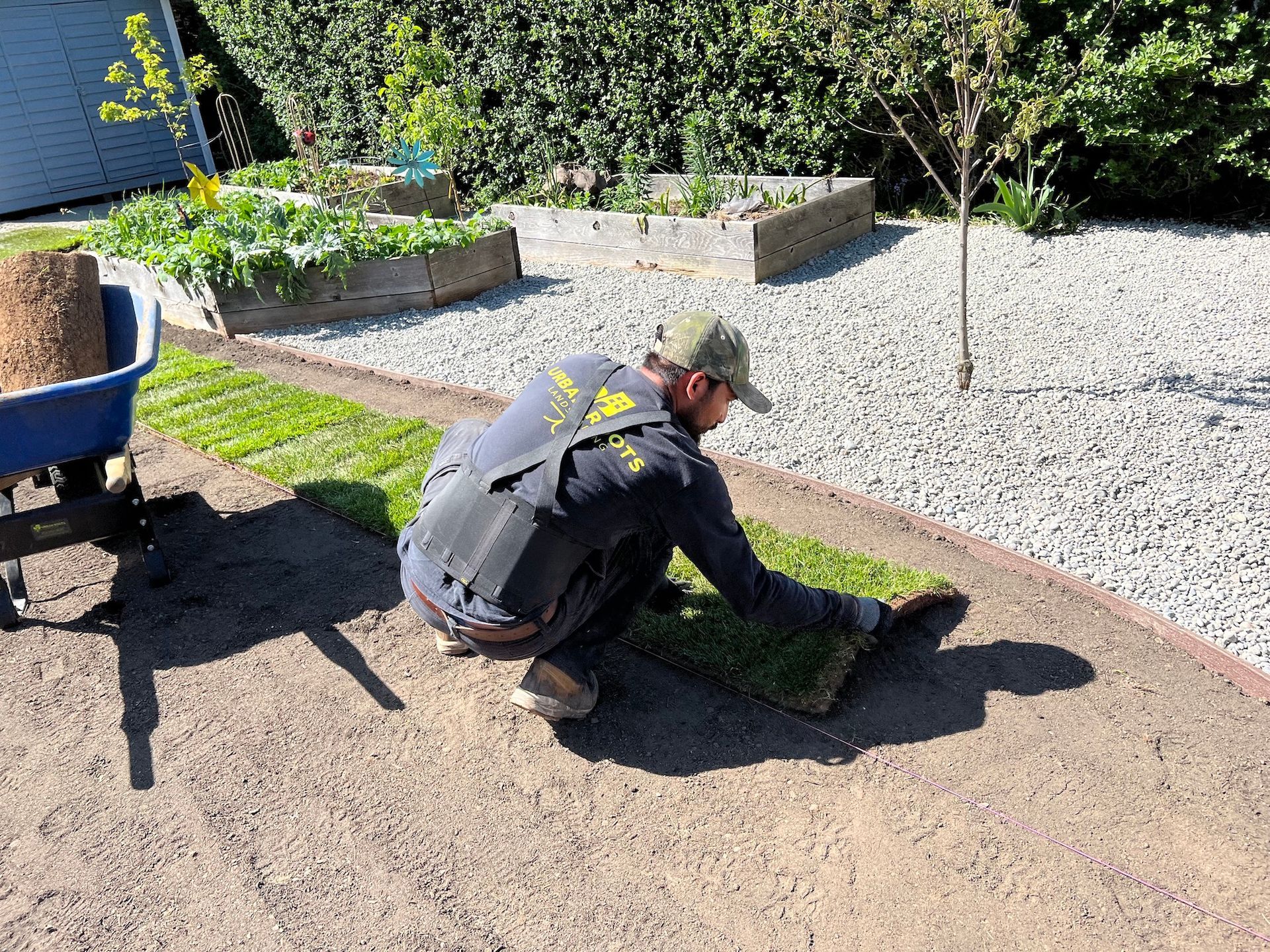 A man is kneeling down in the dirt in a garden.