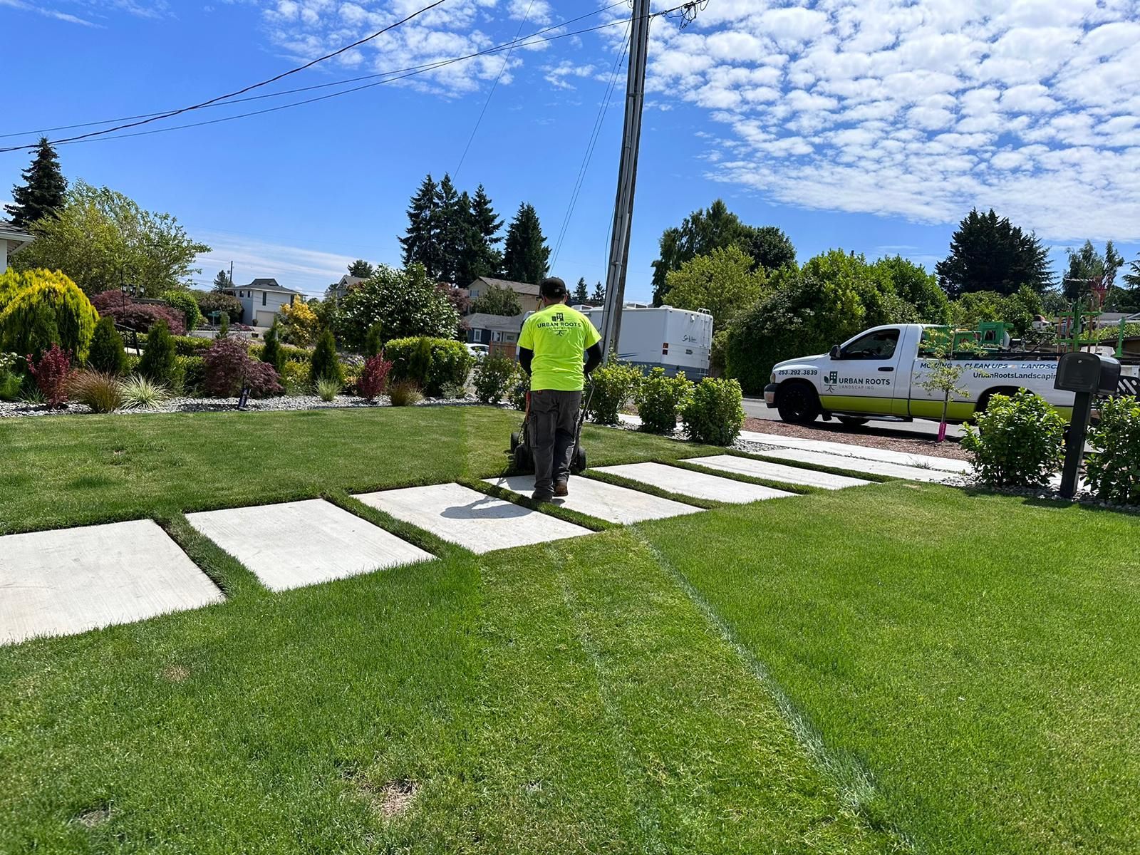 A man is standing in a lush green lawn next to a truck.