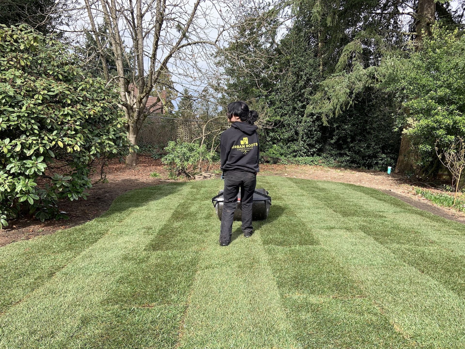 A man is mowing a lush green lawn with a lawn mower.