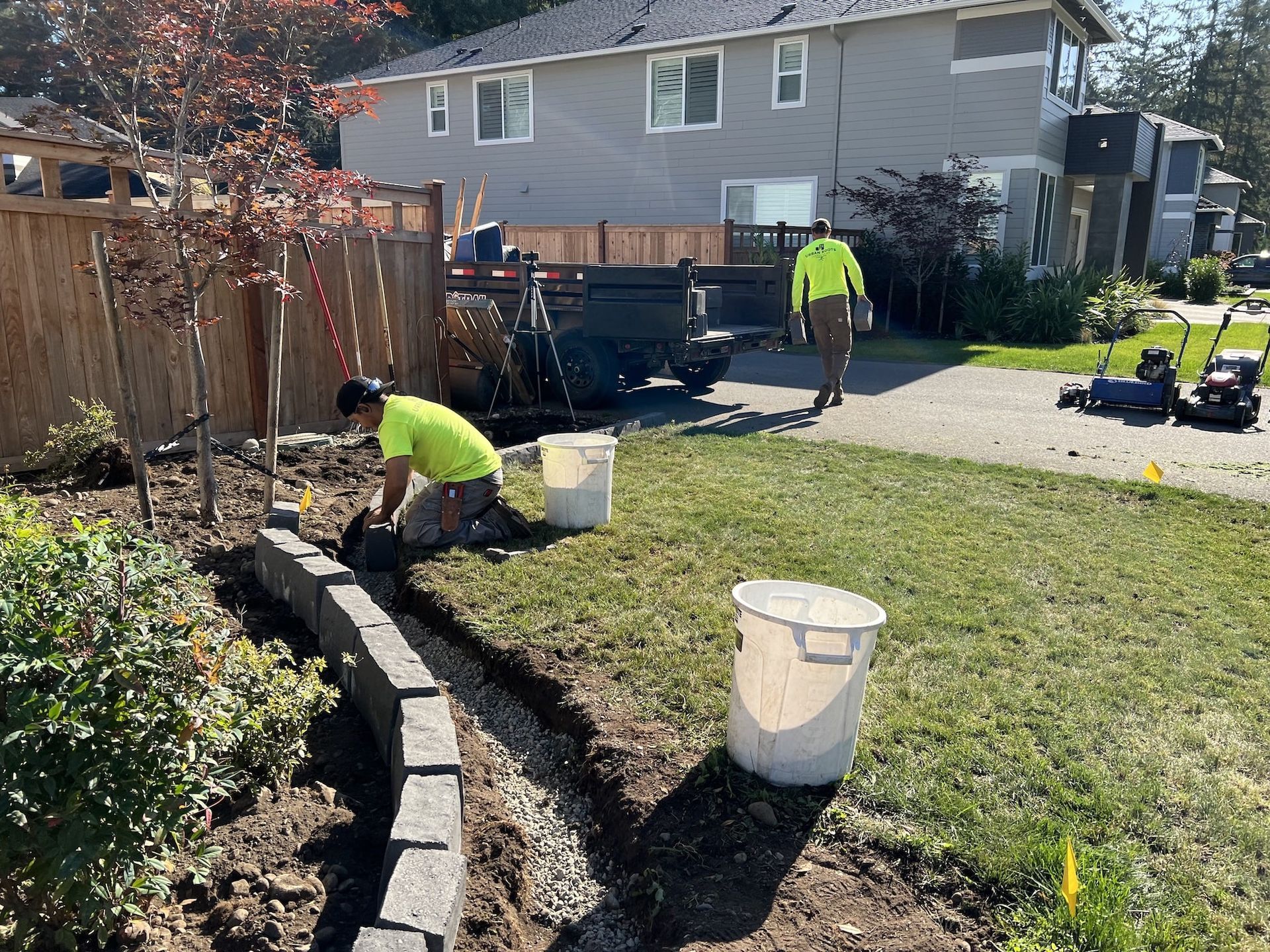 A man is pushing a lawn mower down a lush green lawn.