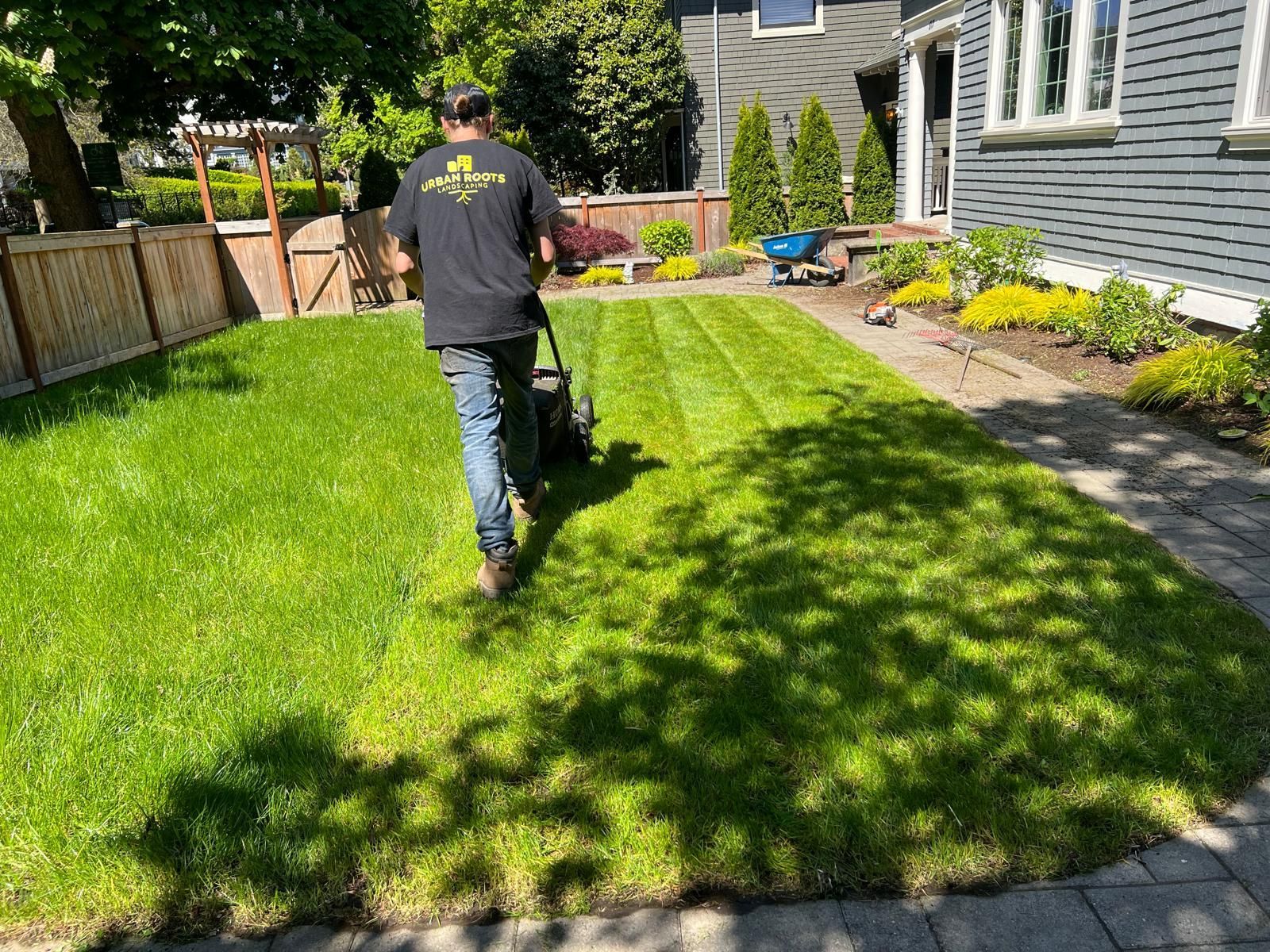 A man is mowing a lush green lawn in front of a house.
