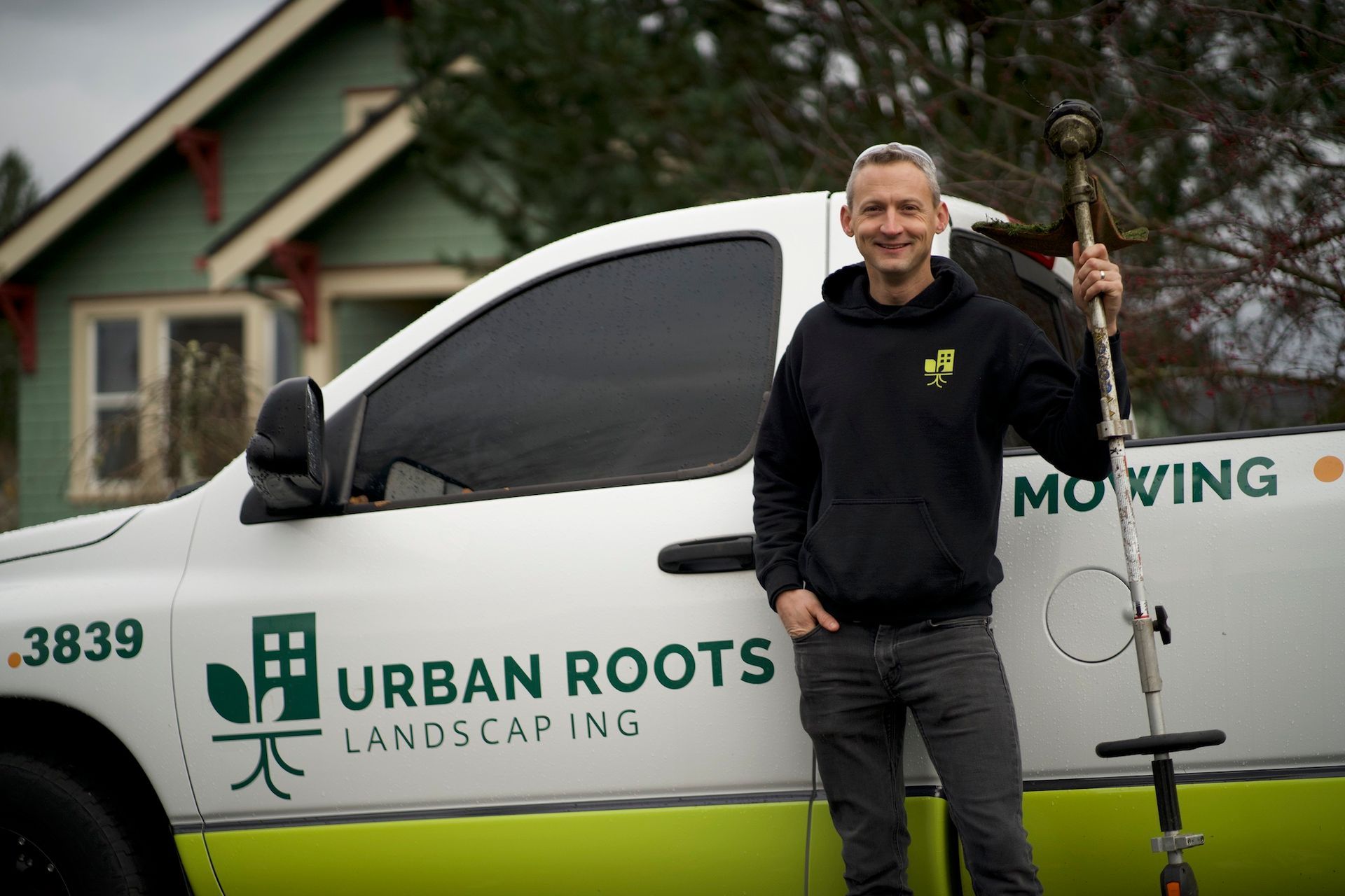 A man is standing in front of a truck that says urban roots landscaping.