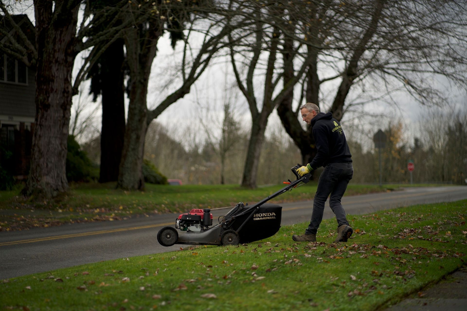 A man is mowing the grass on the side of the road.