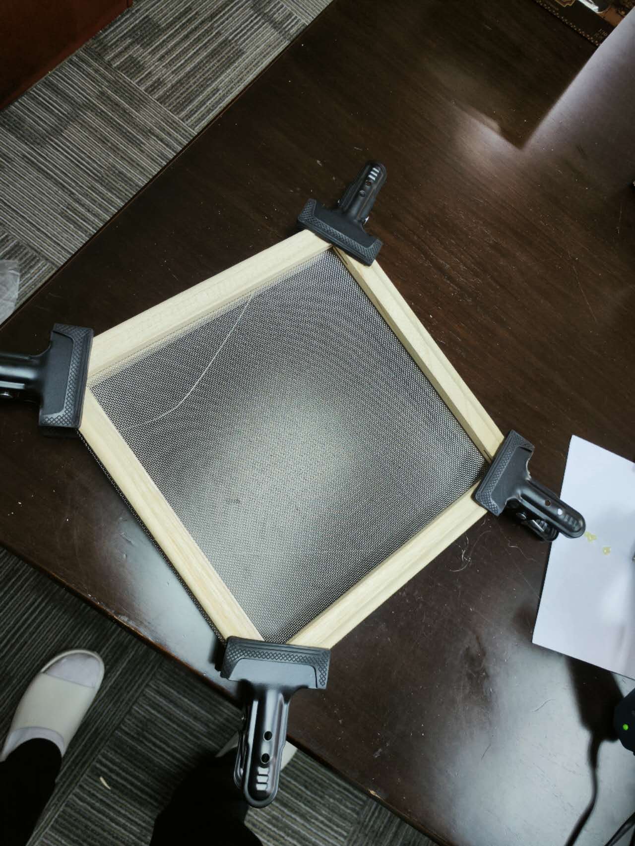 A piece of wire mesh is sitting on top of a wooden table.