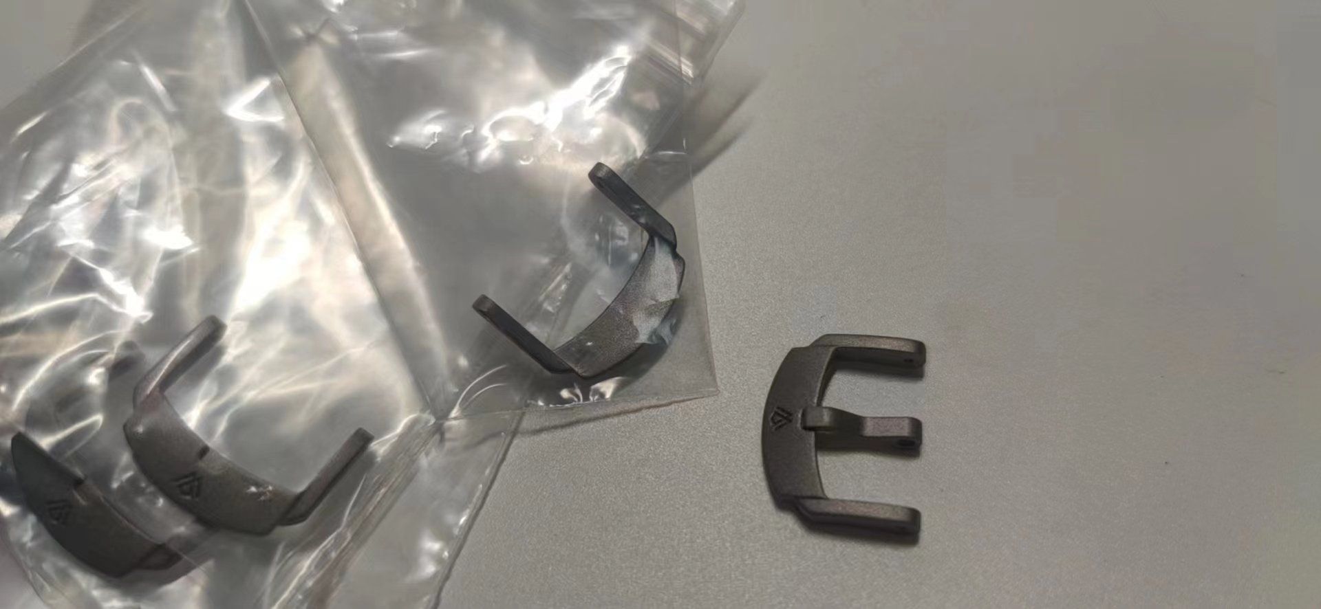 A pair of broken watch straps in plastic bags on a table.