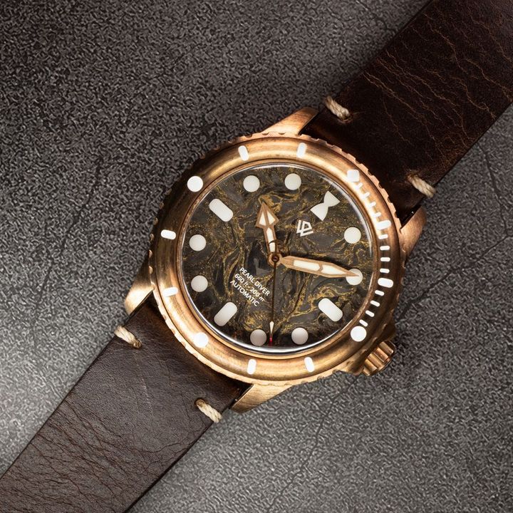 A watch with a brown leather band is on a table