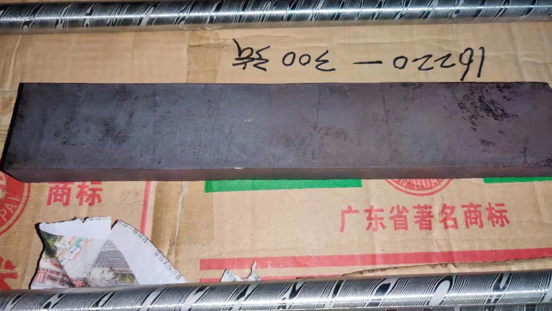 A piece of metal is sitting on top of a cardboard box with chinese writing on it.