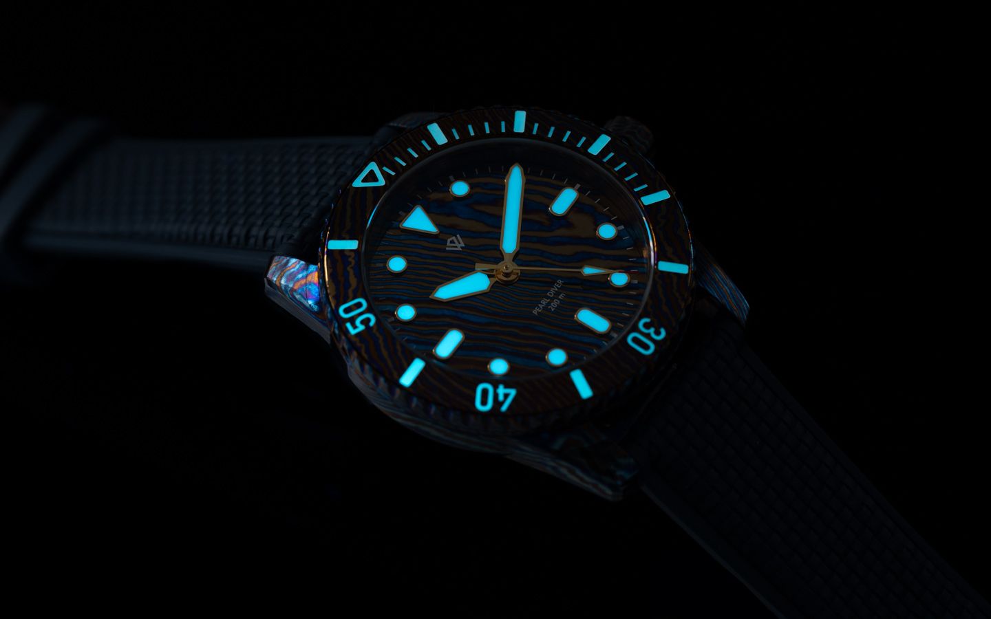 Luminous dive watch glowing blue in the dark, black band and bezel, white numerals.