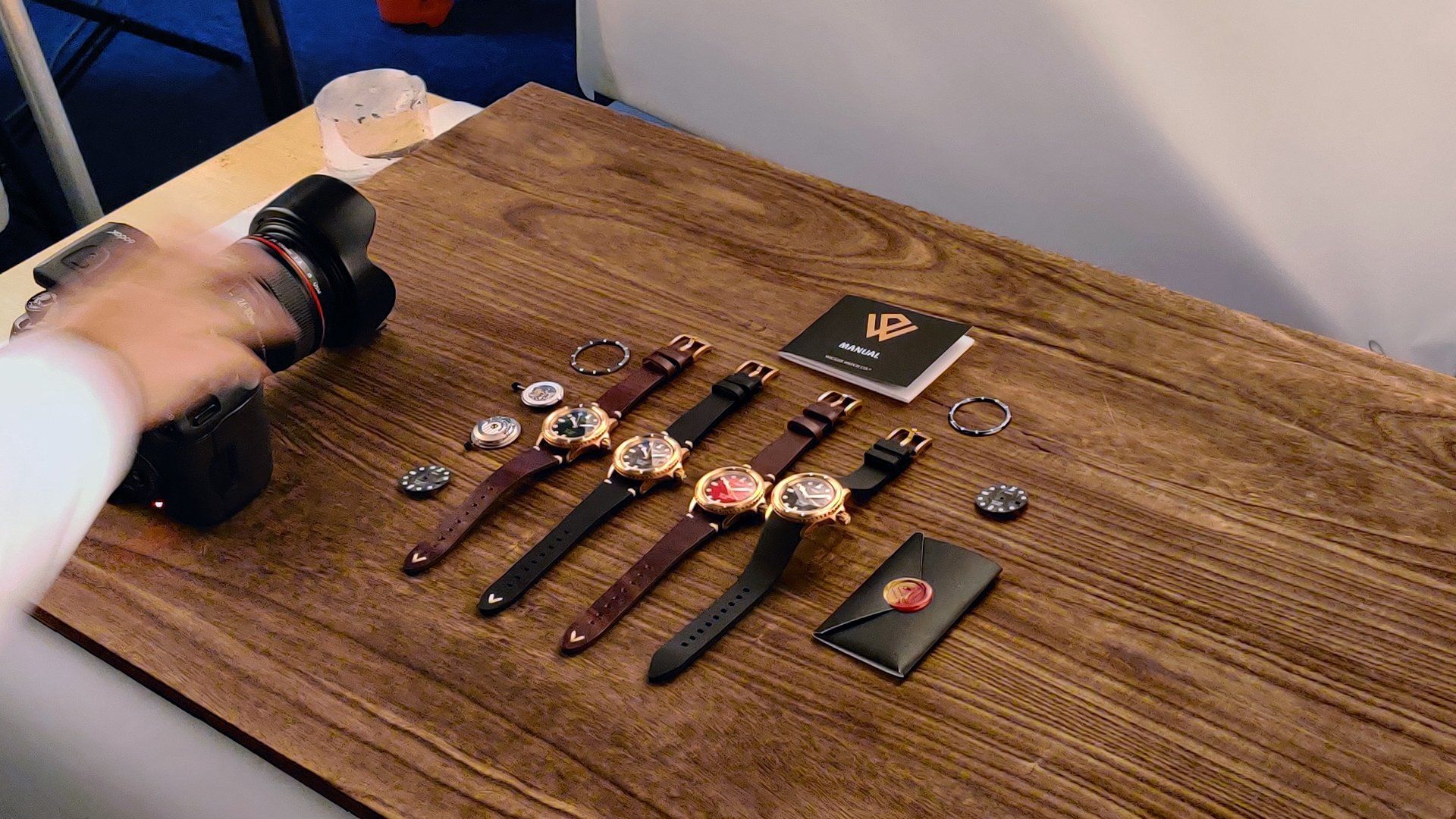 A person is taking a picture of watches on a wooden table.