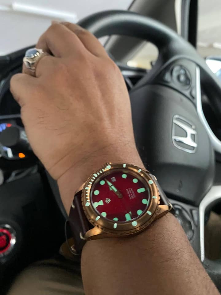 A man wearing a watch is driving a honda