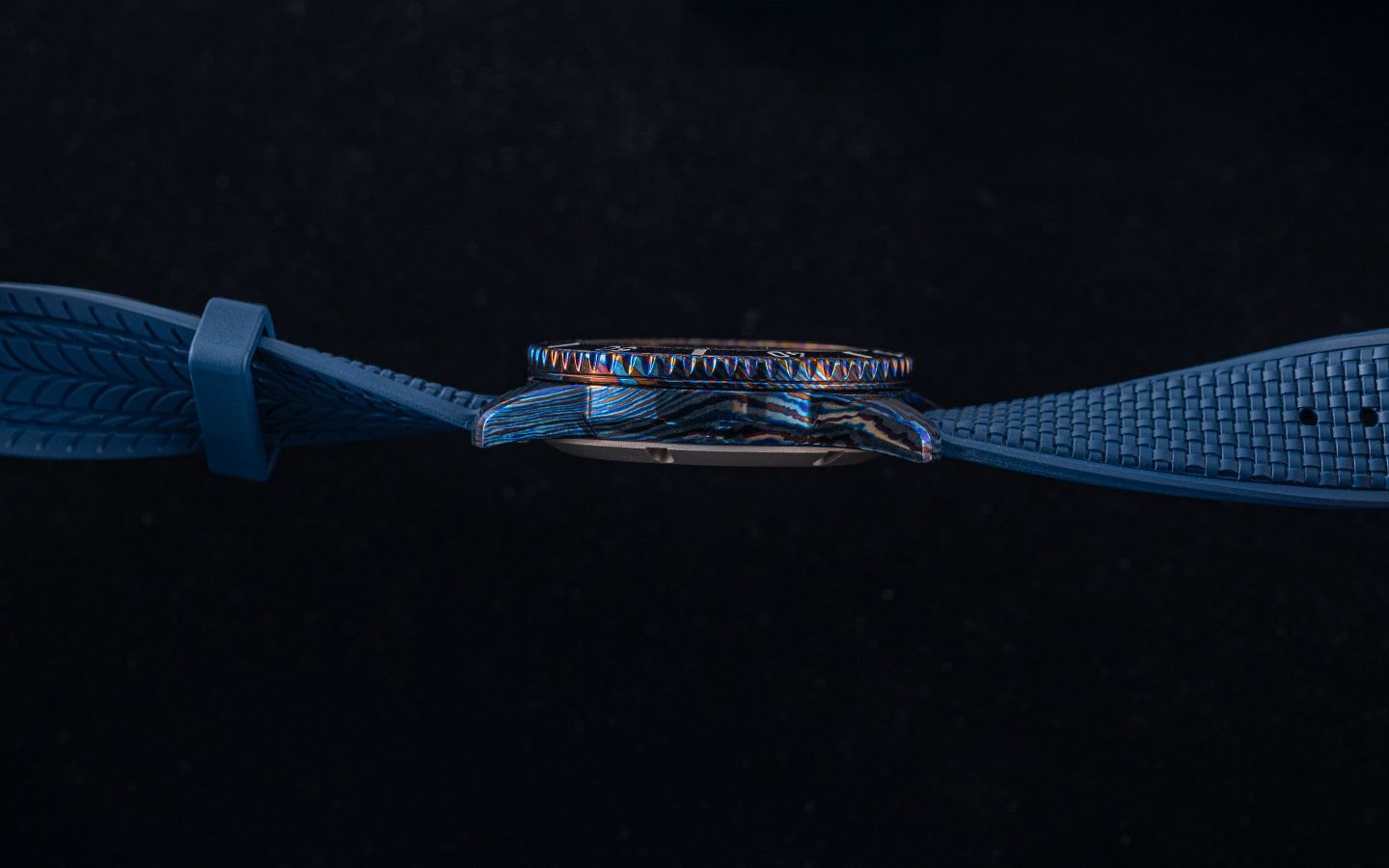 Side view of a blue wristwatch with a textured strap against a black background.