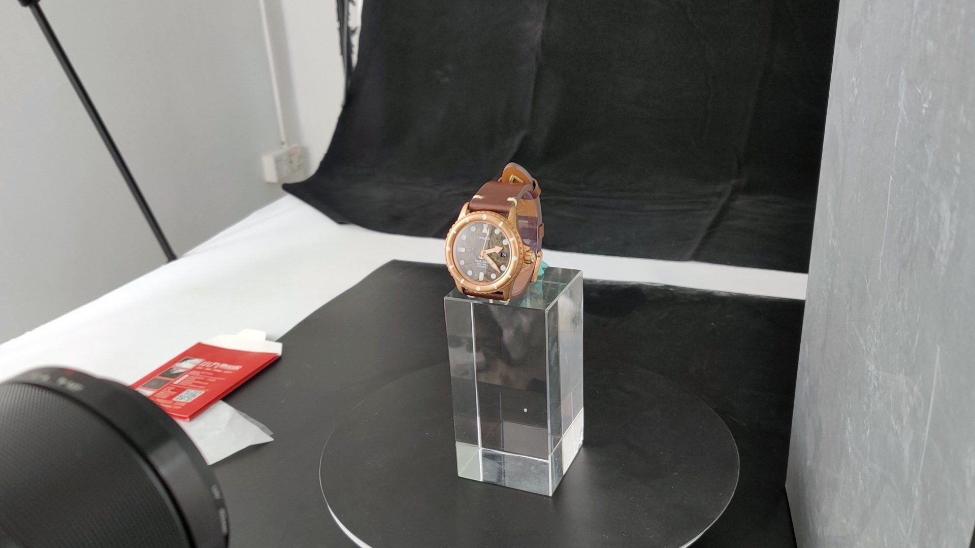 A watch is sitting on a clear block on a table