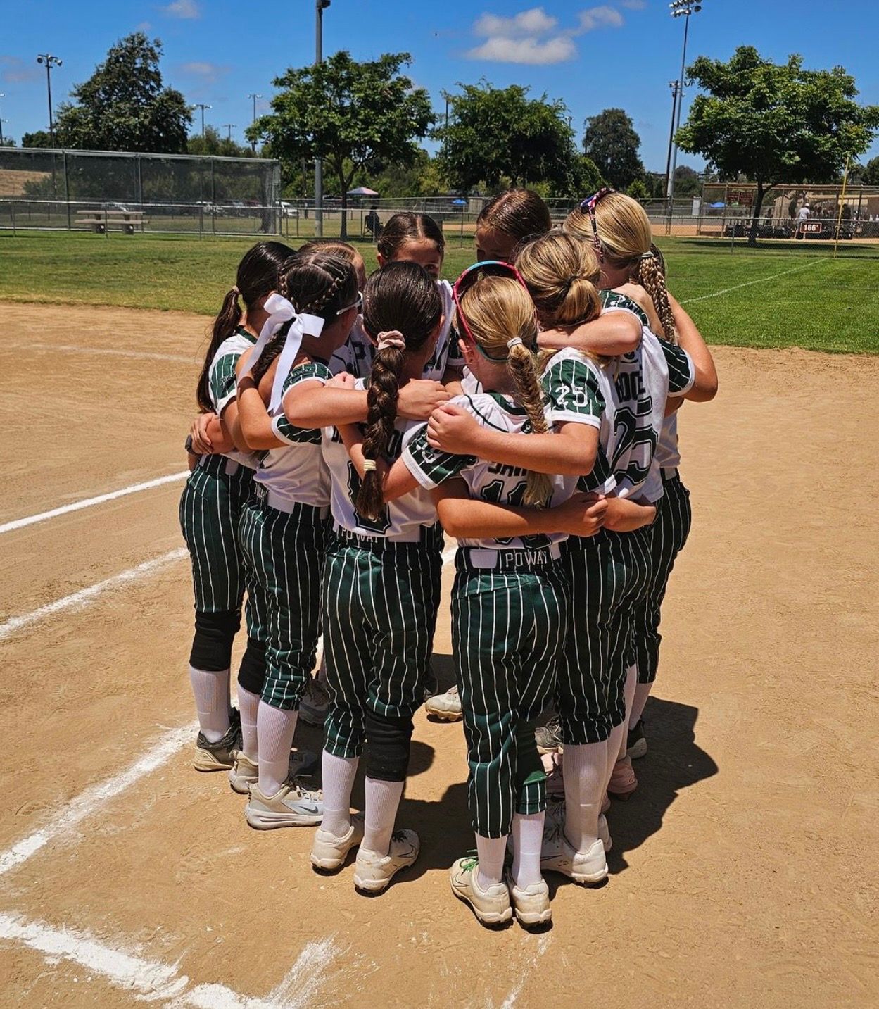 Image with a group of softball player girls huddled together on the field