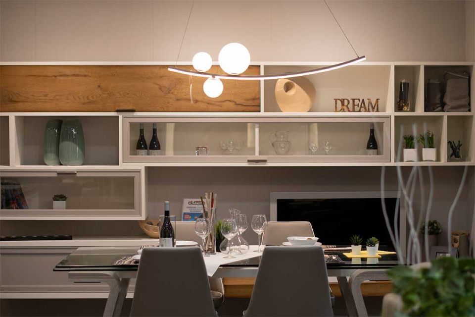 sala da pranzo con tv e pensili bianchi e in legno