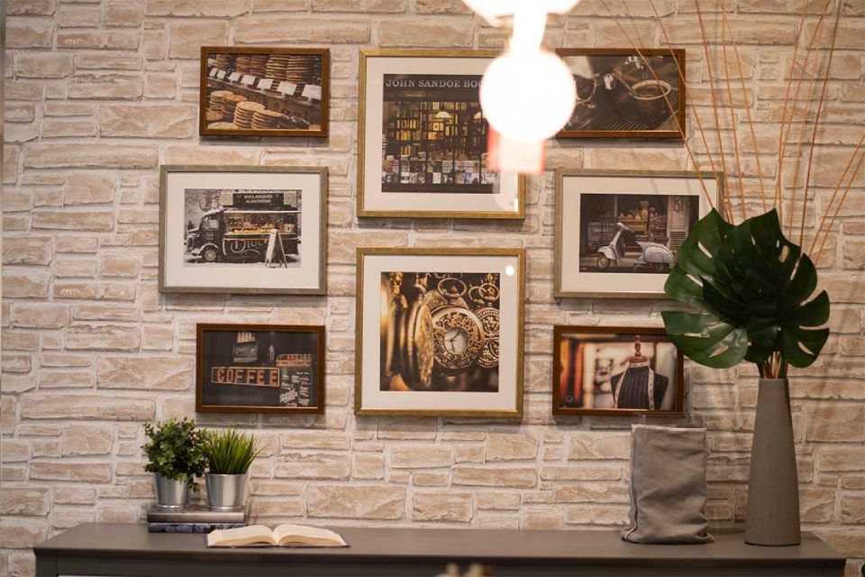 cornici appese su parete di mattoncini beige