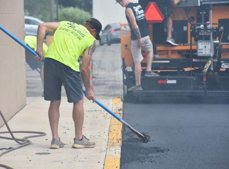 A man in a neon yellow shirt is holding a broom in front of a machine.