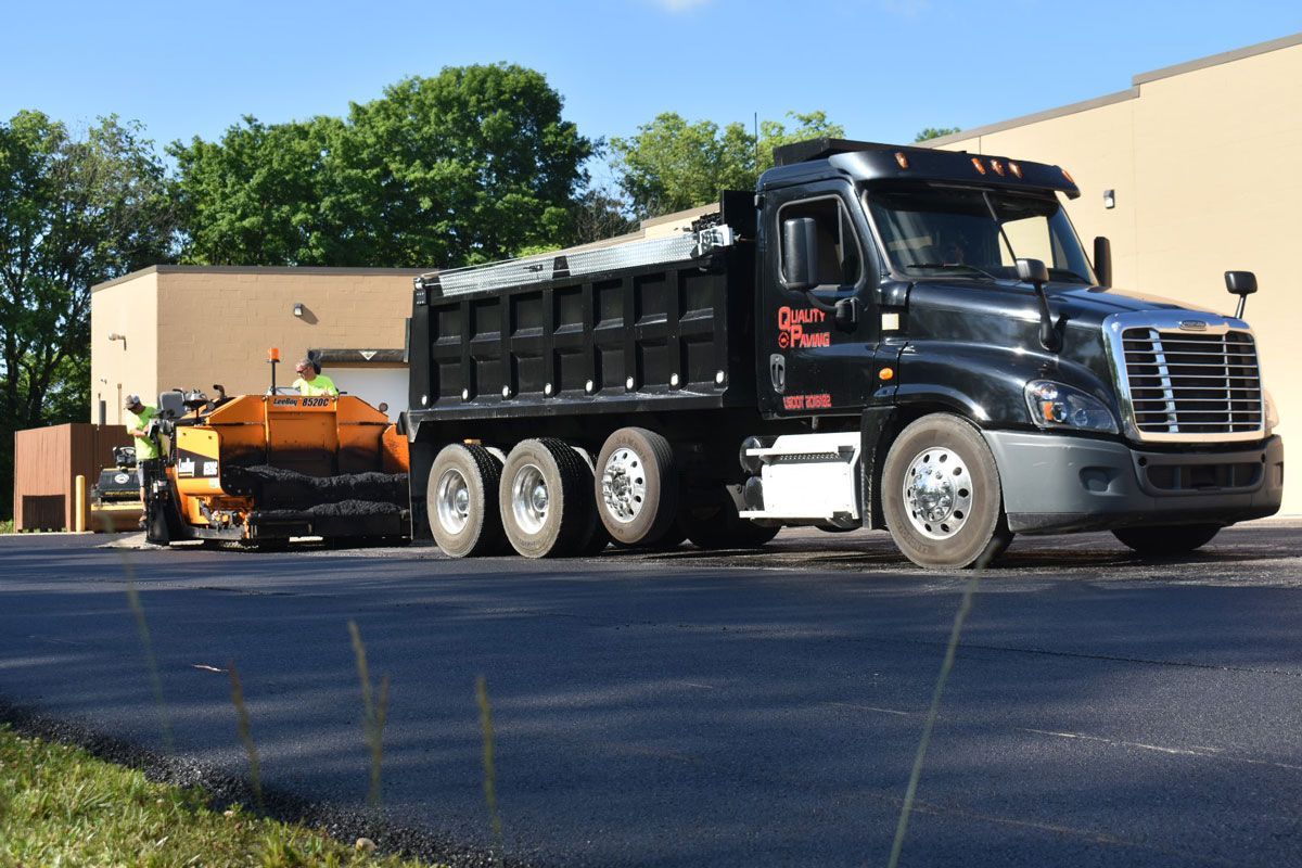 A dump truck is driving down a road next to a building.