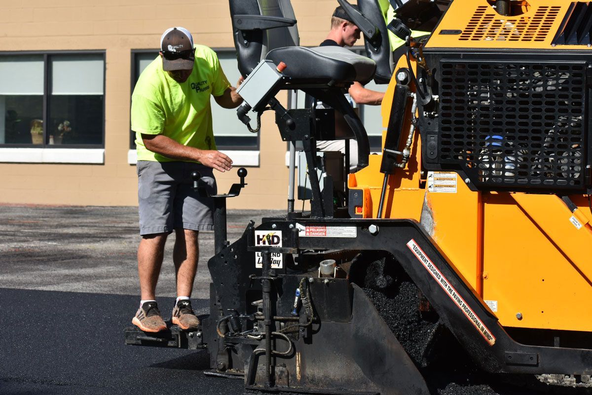 Two men are working on a machine that is laying asphalt.