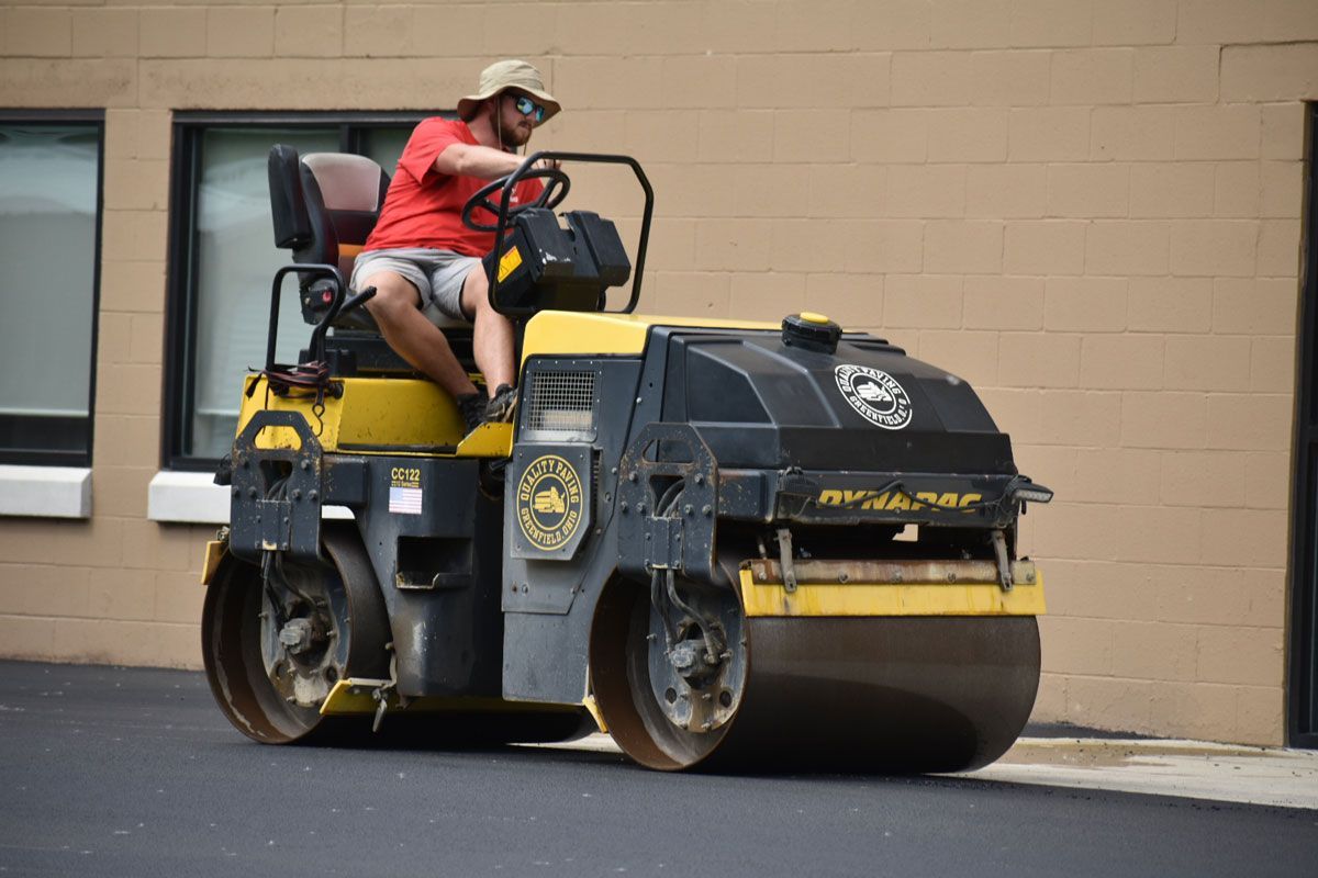 A man is driving a roller on a road.