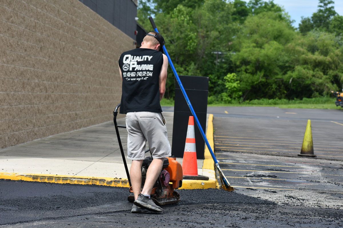 A man is using a broom to clean a parking lot.