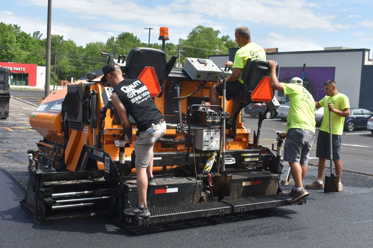 A group of men are working on a machine in a parking lot.