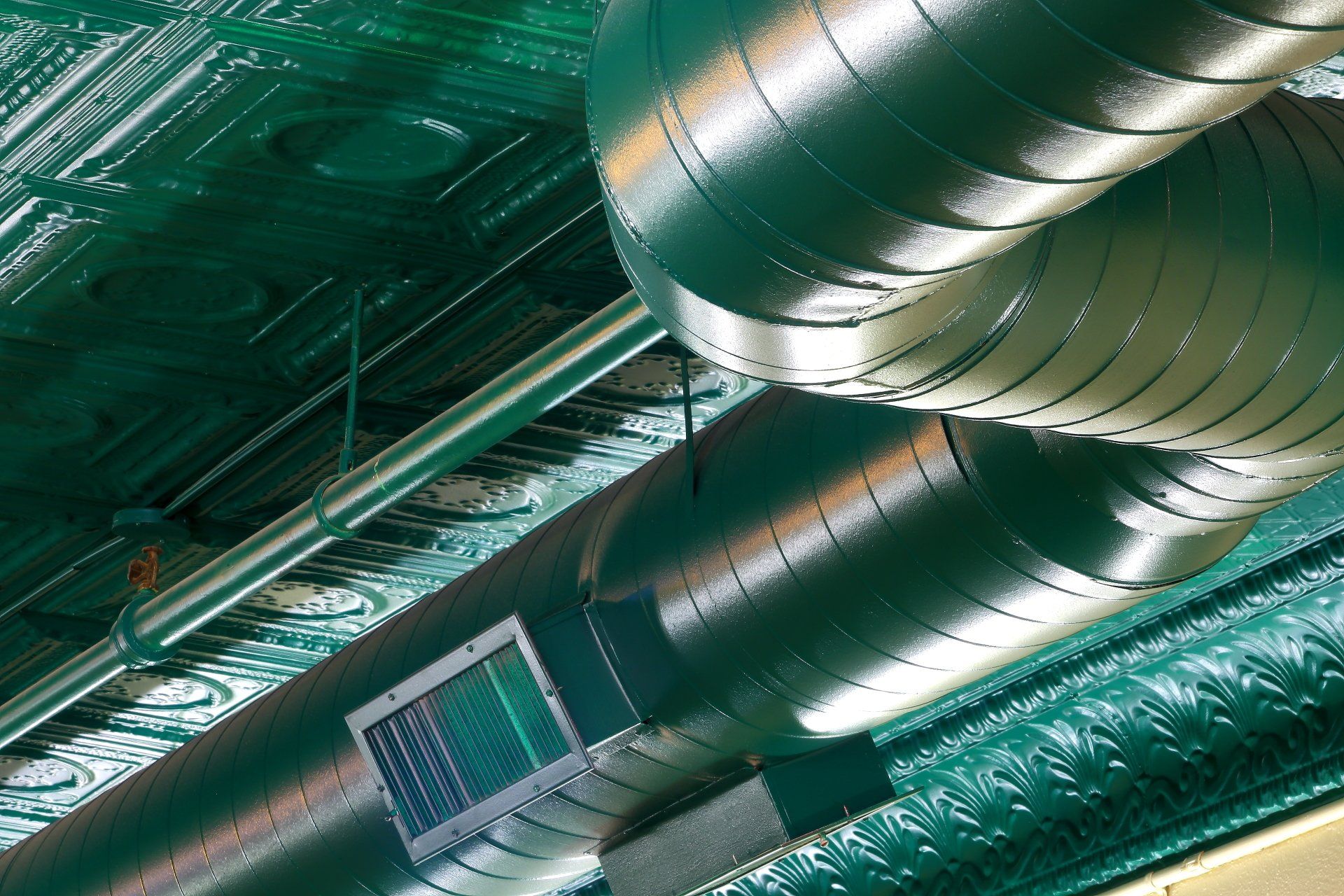 A bunch of metal pipes are hanging from the ceiling of a building