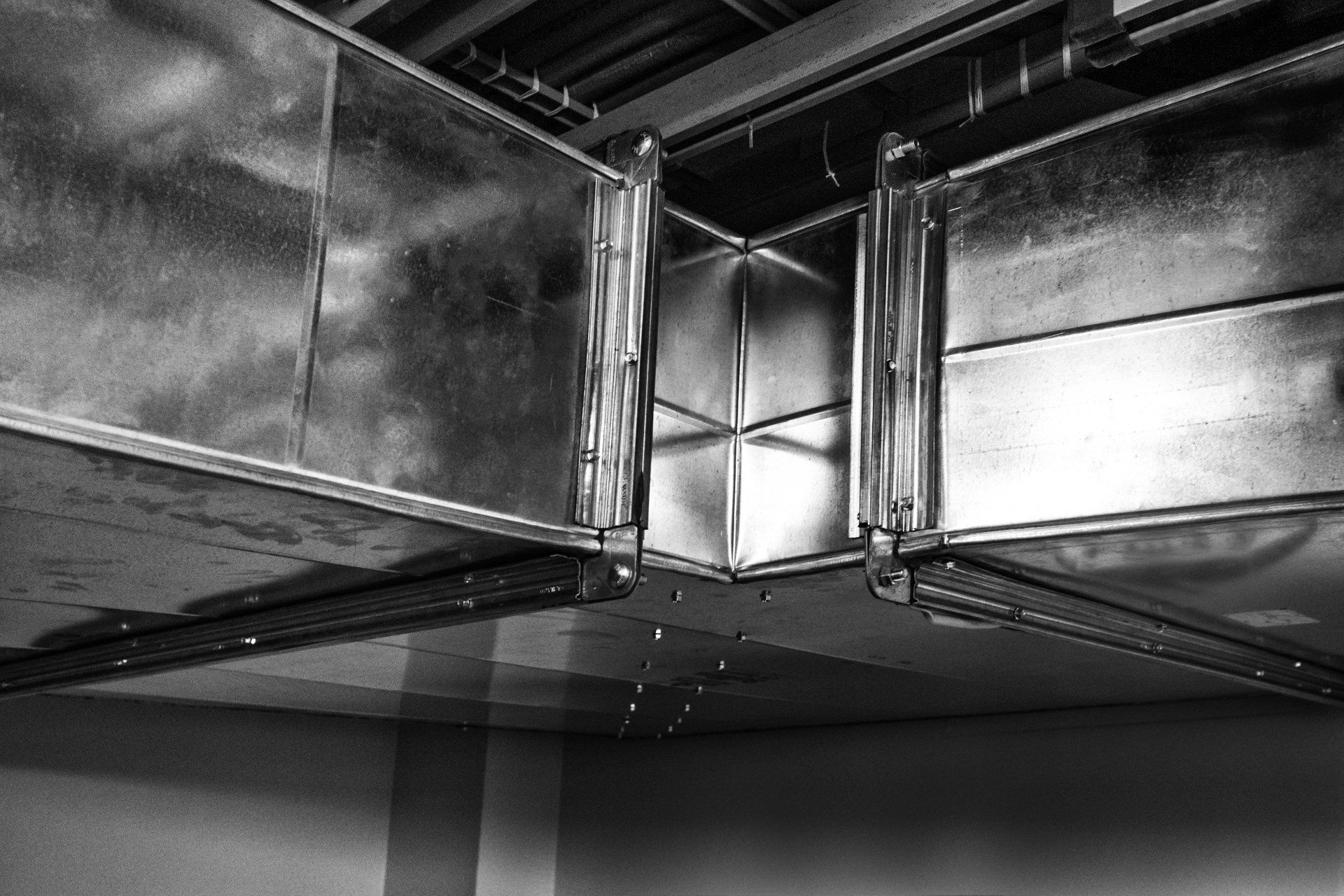 A black and white photo of a metal duct in a building.