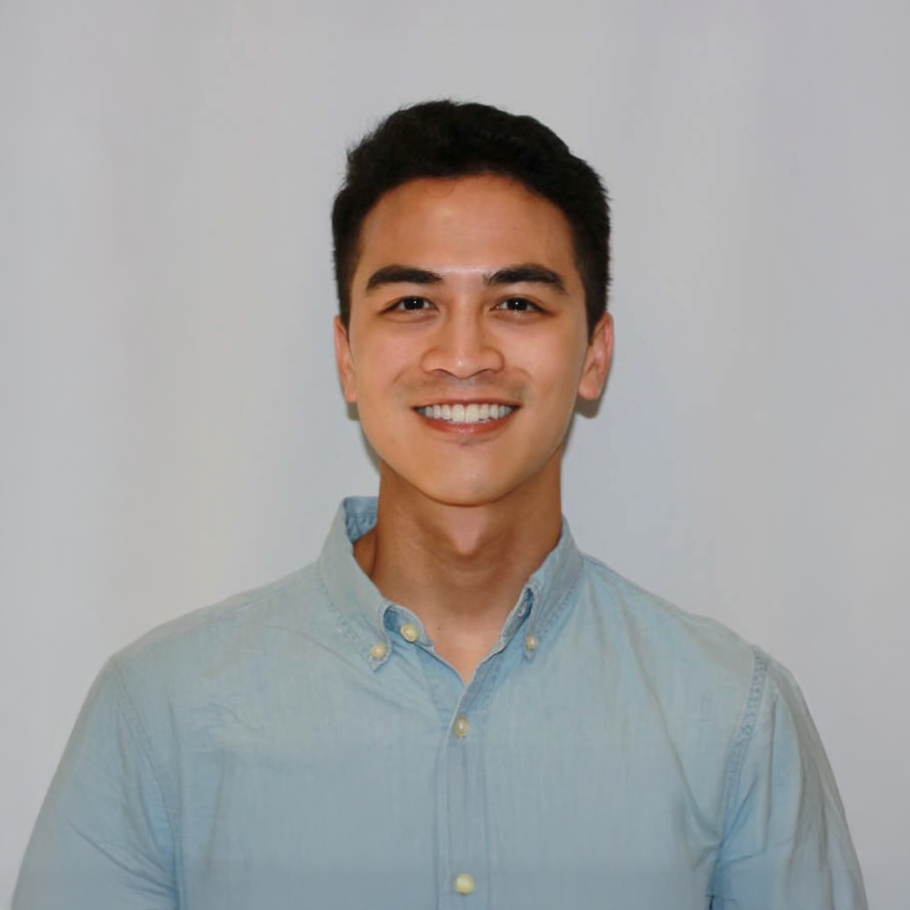 Young man with dark hair and a light blue shirt smiles at the camera.