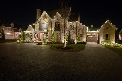 A large house with christmas lights on it is lit up at night.