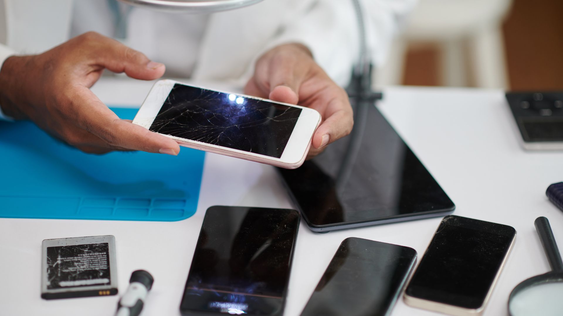 A person is holding a cell phone with a broken screen.