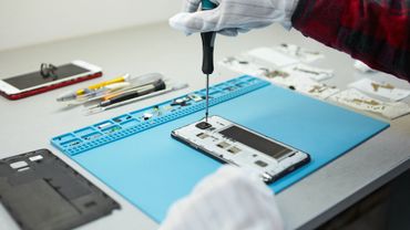 A person is fixing a cell phone with a screwdriver.