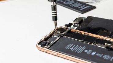 A close up of a cell phone being repaired with a screwdriver.