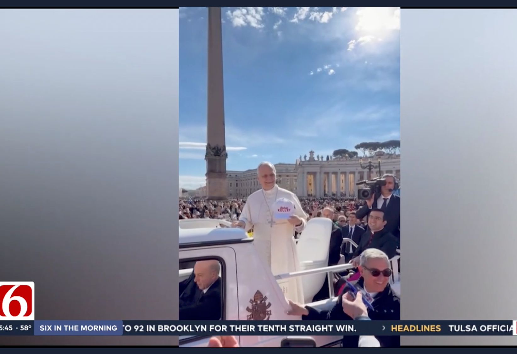 Pope Francis rides in a popemobile through St. Peter’s Square in Vatican City, holding a white hat that says 
