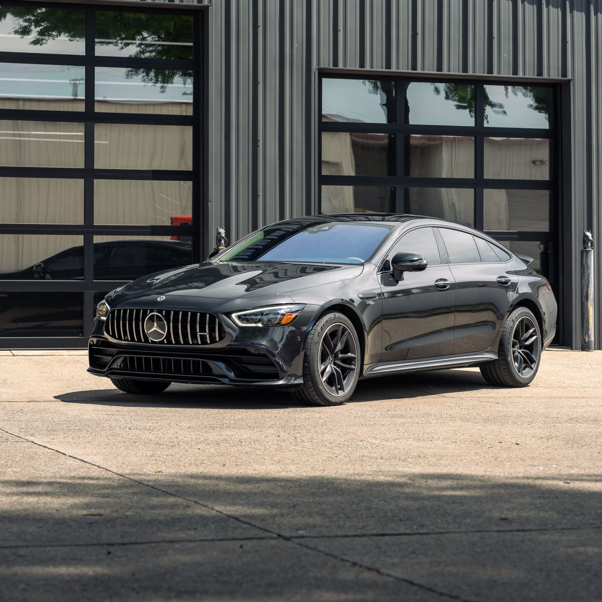 Black luxury sedan parked outside a building with large windows.