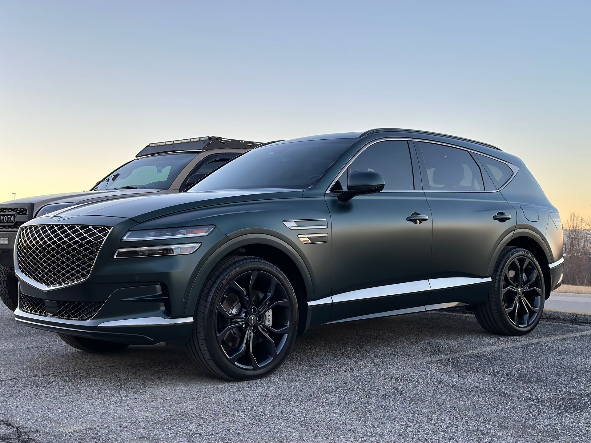 Two cars are parked next to each other on a gravel road.