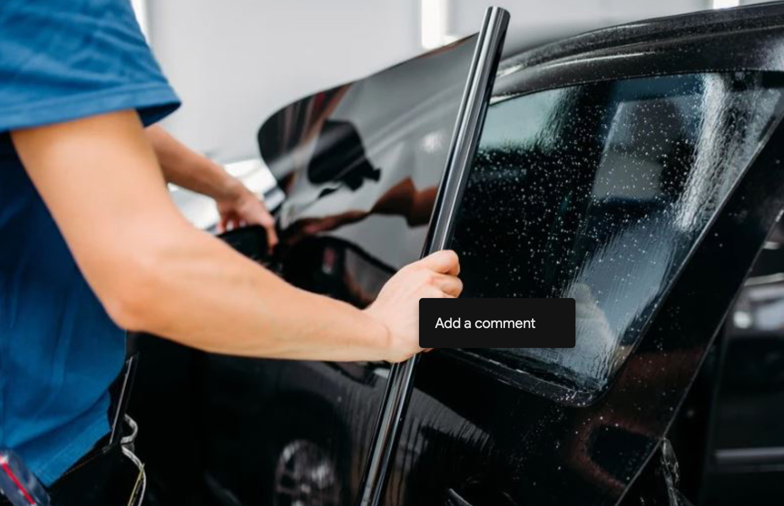 A man is applying window tinting to a black car.