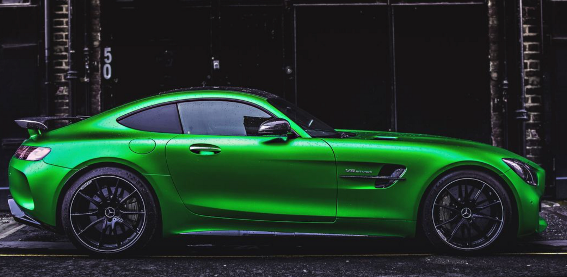 A green mercedes amg gt r is parked in front of a building.